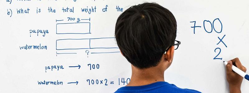 Image showing boy solving maths problem on a whiteboard
