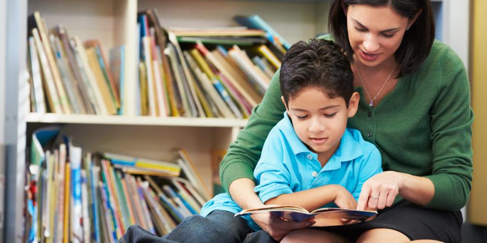 image of a woman helping a child learn to read