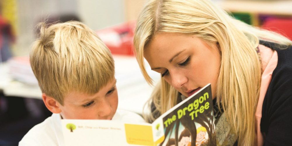 Image showing a teacher and child reading a book together